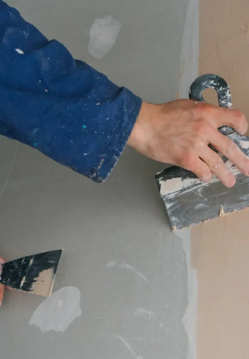 plasterer-man-works-plastering-two-trowels-plasterboard-blue-uniform