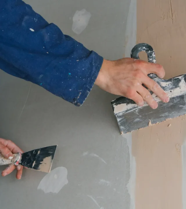 plasterer-man-works-plastering-two-trowels-plasterboard-blue-uniform